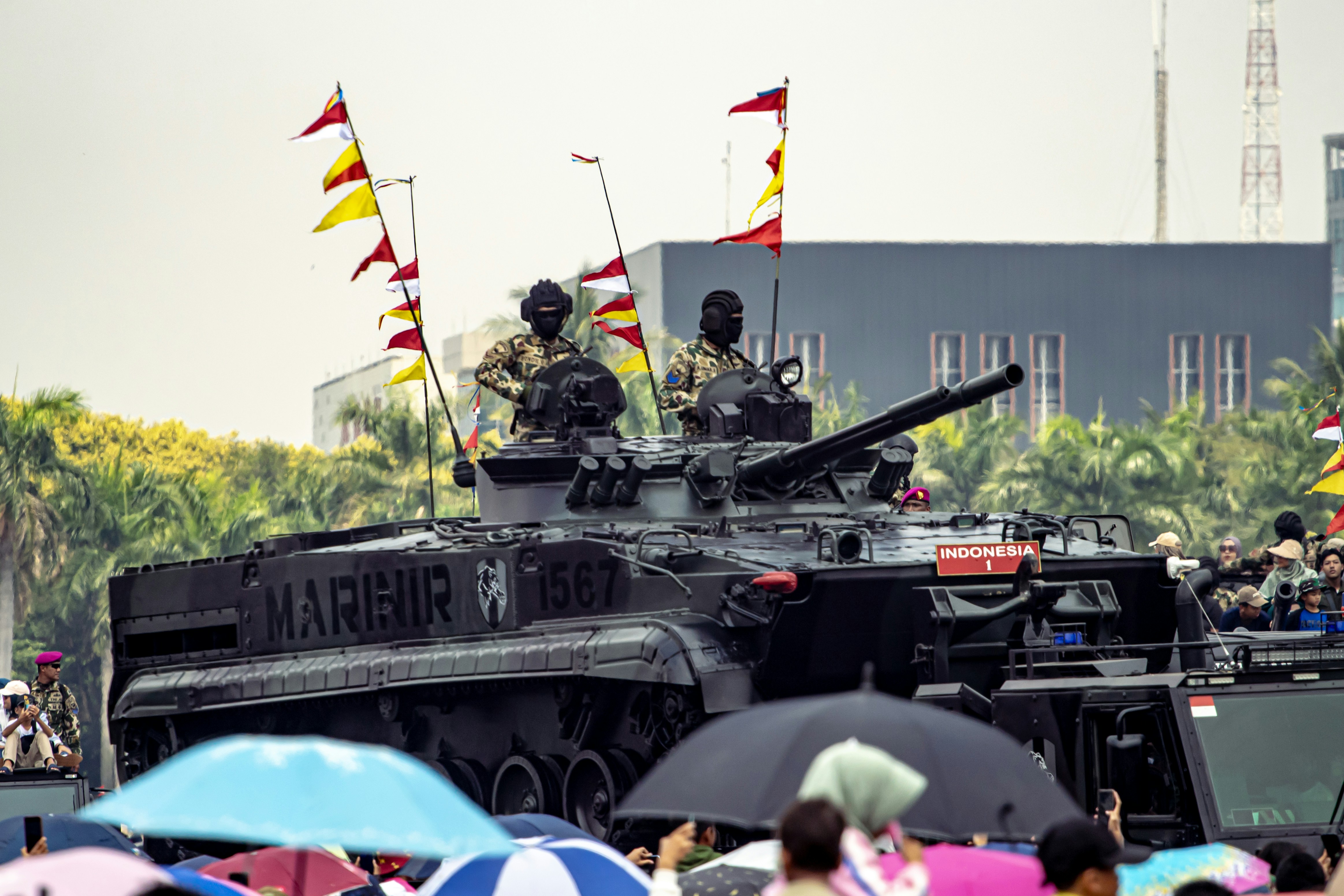 A military tank driving through a crowd of people