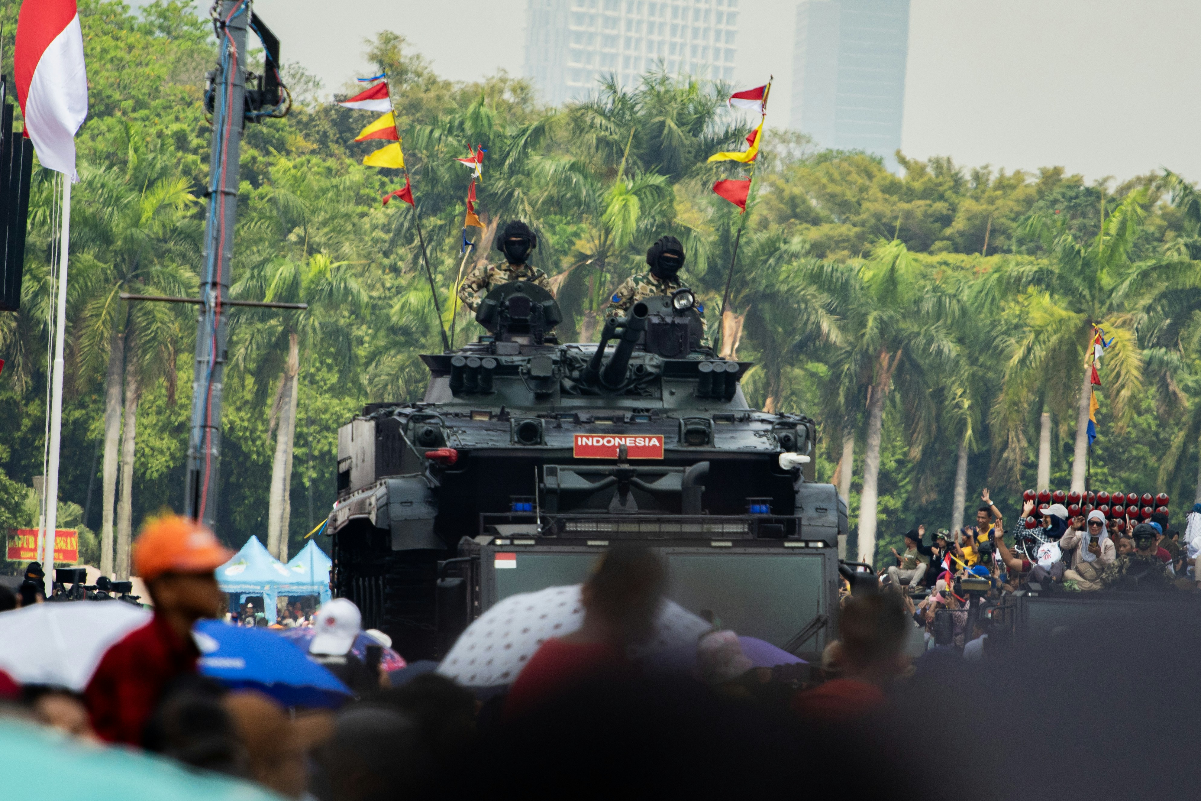 A tank driving down a street with people watching