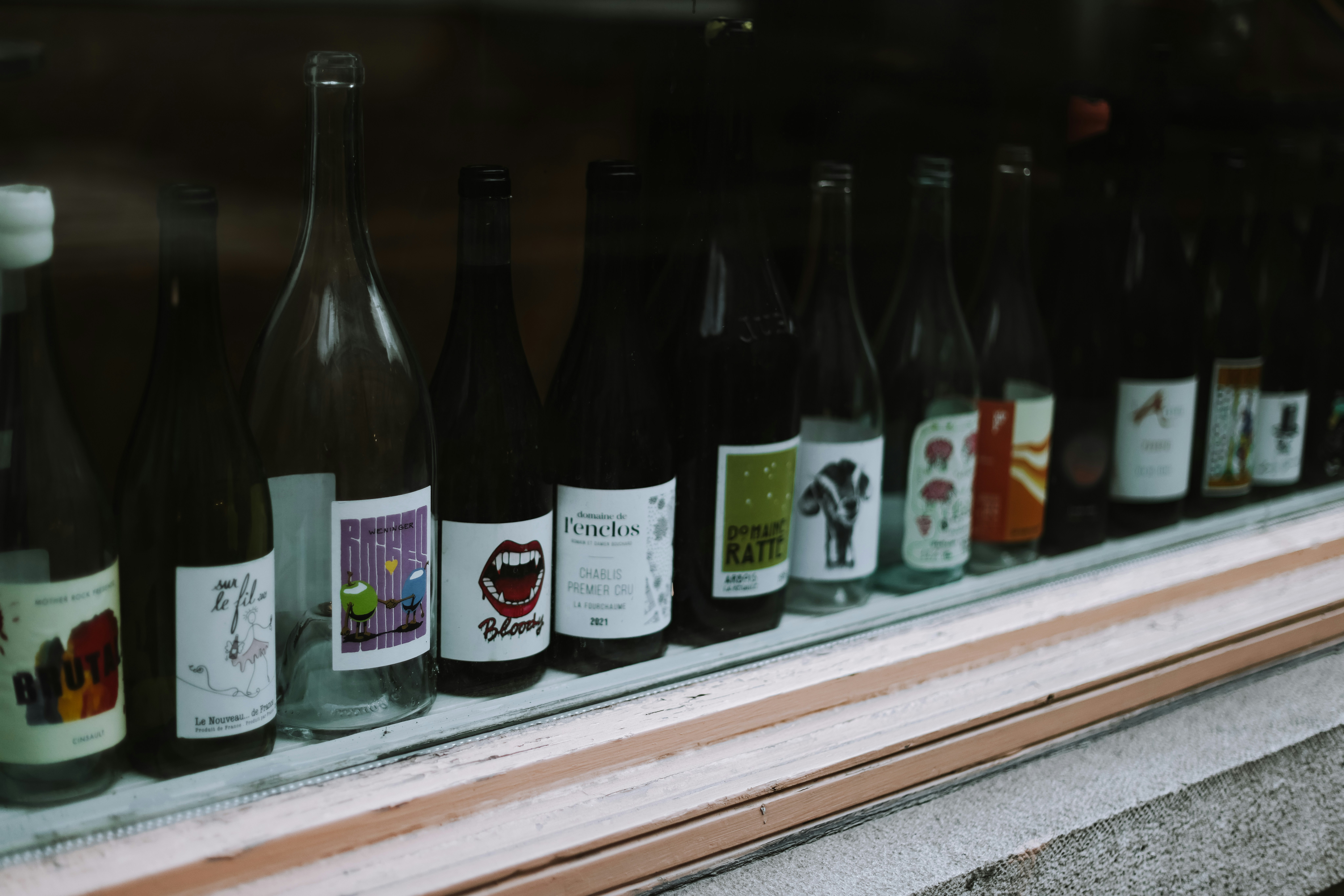A row of wine bottles sitting on top of a window sill