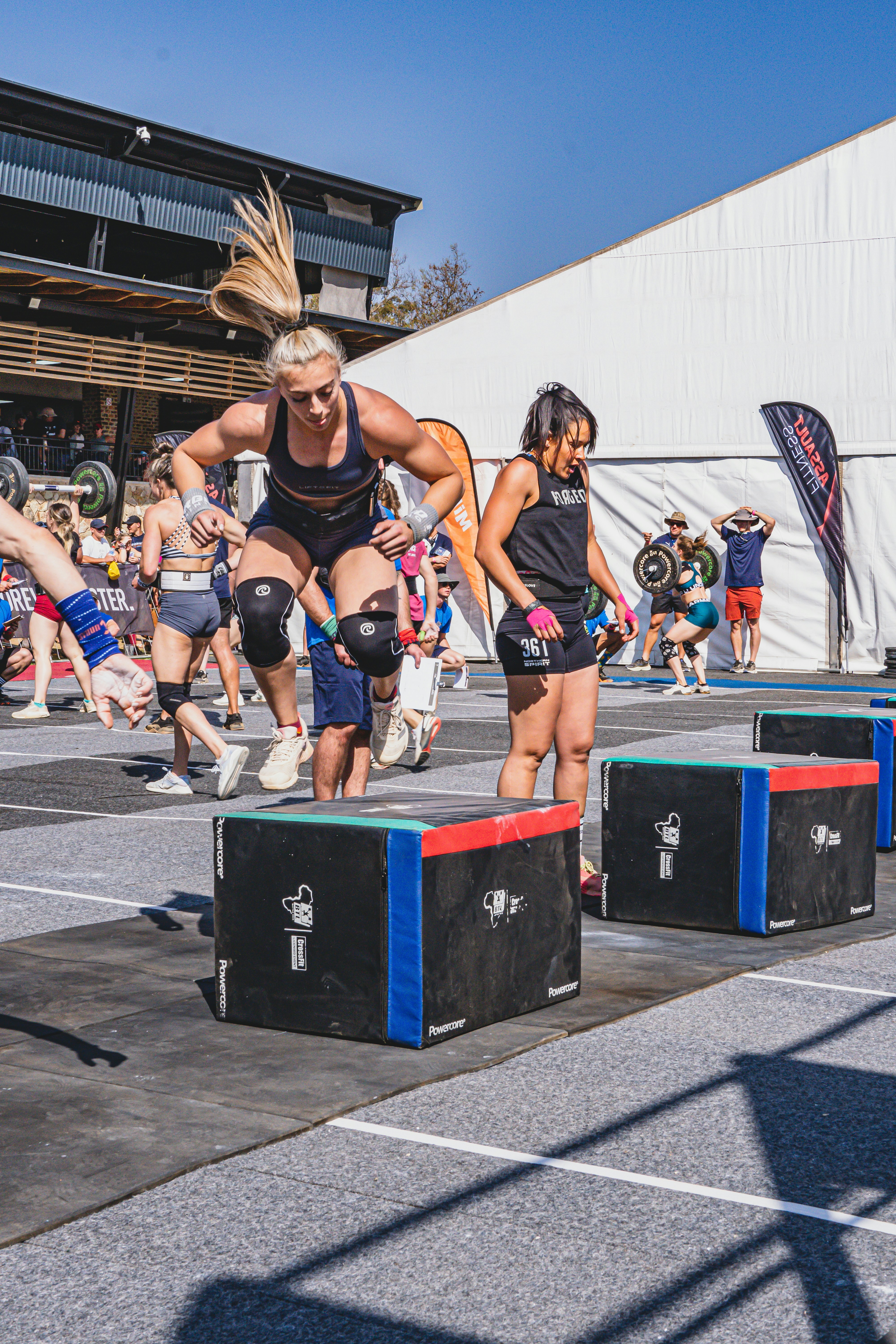 Athlete doing box jumps in bright gym, high energy mid-air moment