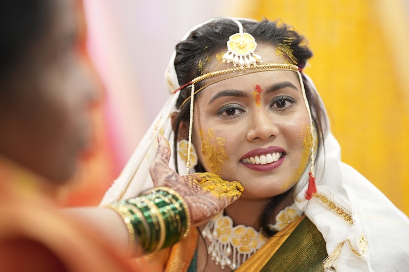 A woman in a yellow and green sari smiles at a man in a red