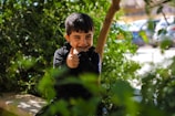 A young boy sitting on a bench with a finger in his mouth