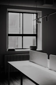 A black and white photo of a desk and a window