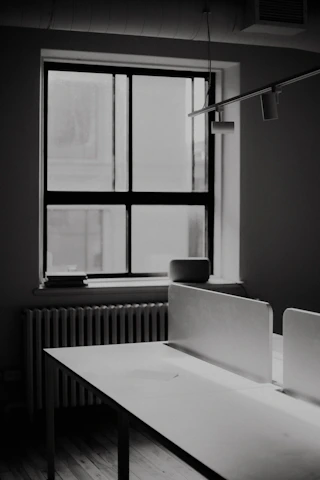 A black and white photo of a desk and a window