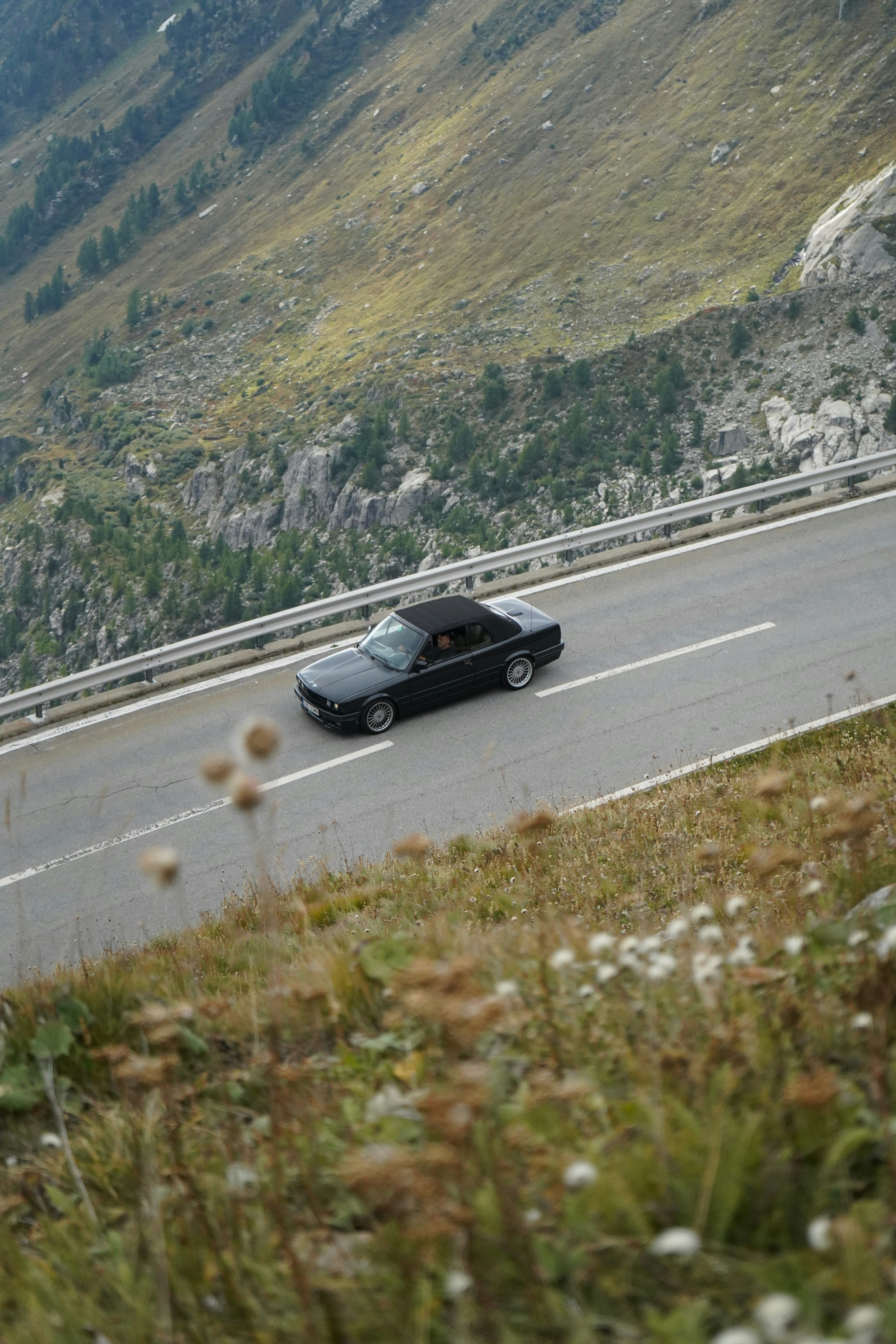 Ein schwarzes Auto, das eine Bergstraße hinunterfährt