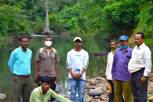 A group of men standing next to each other near a river