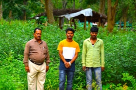 Three men standing next to each other in a forest