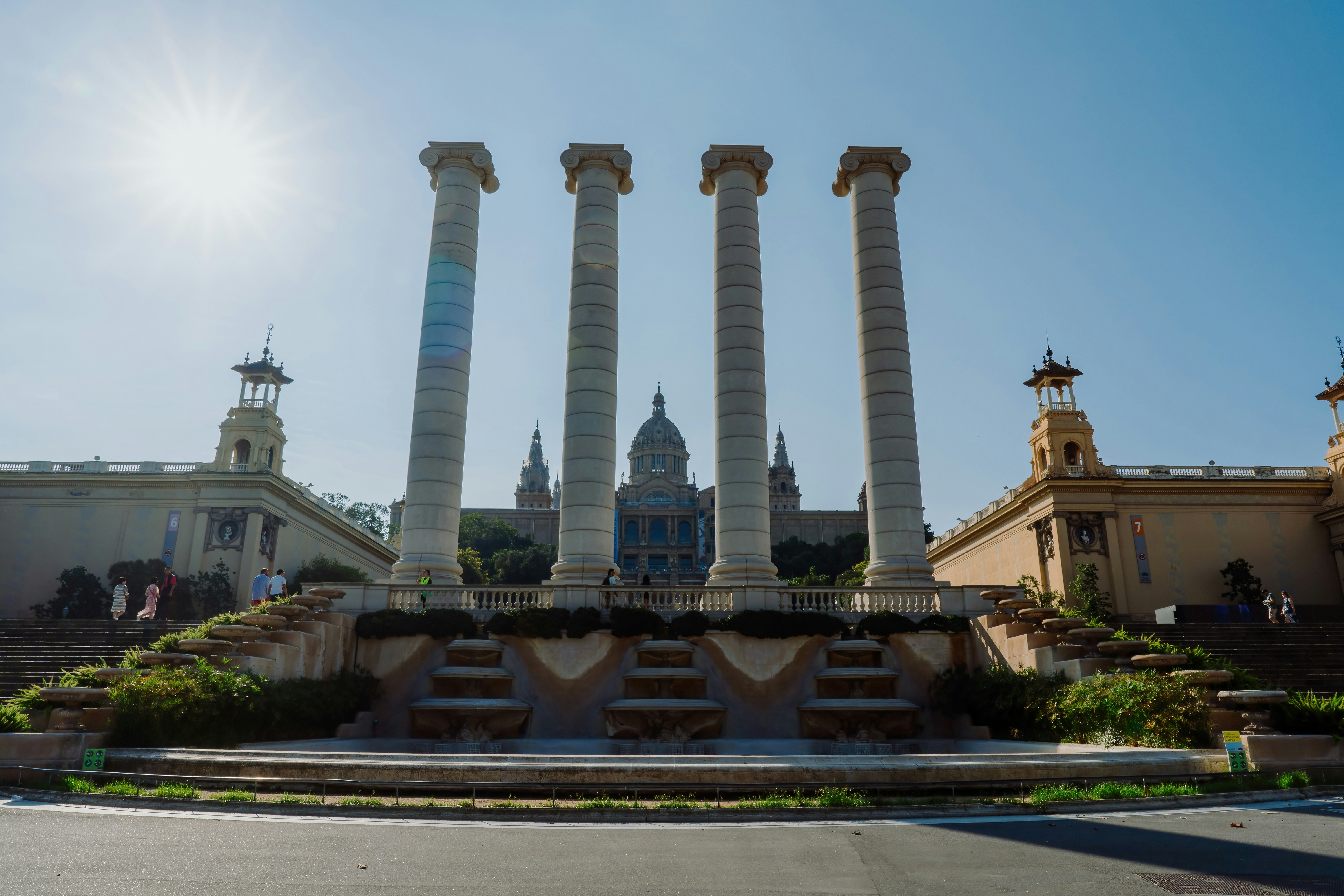 The sun shines brightly over a building with four tall pillars