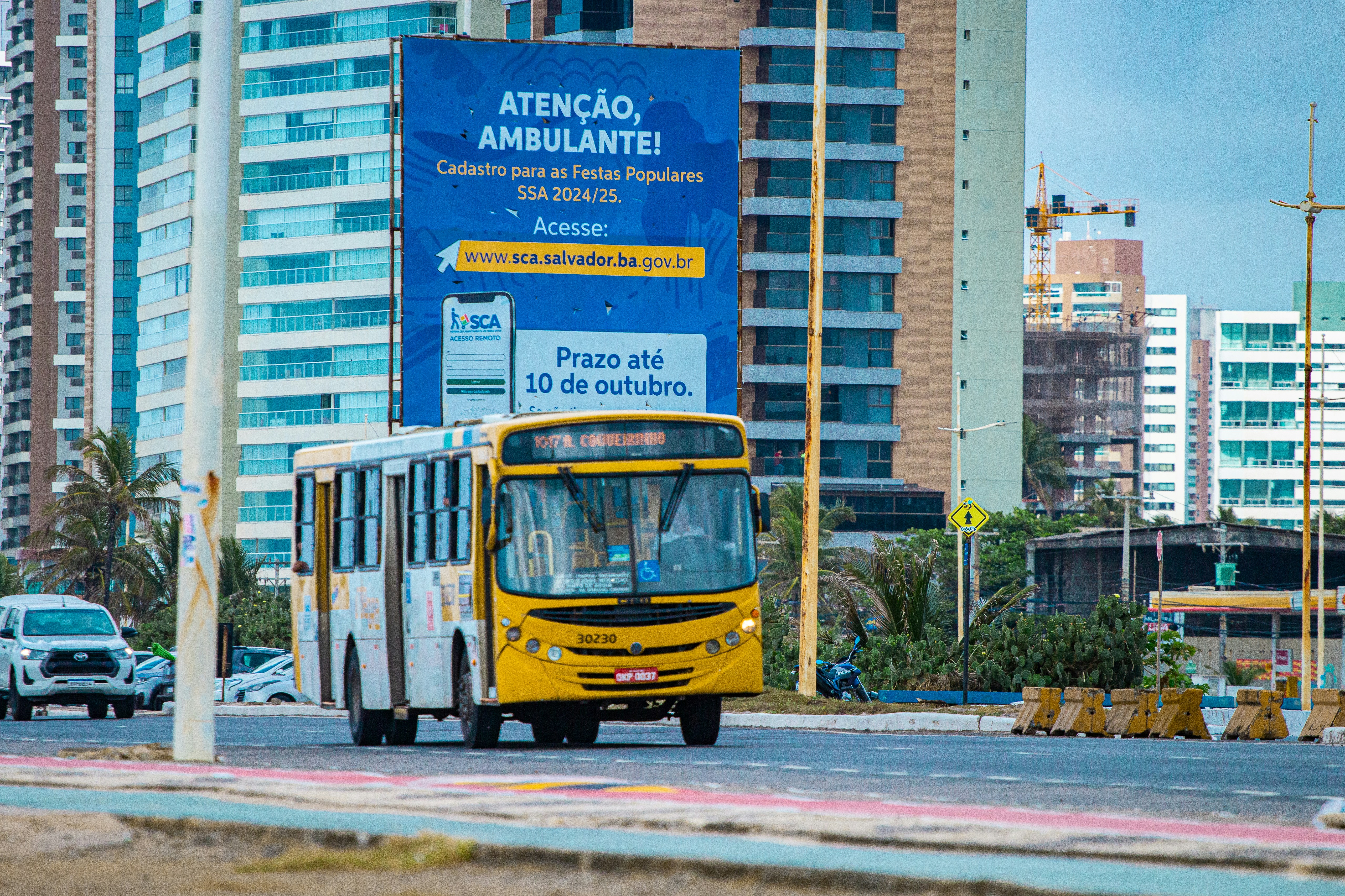 A yellow bus driving down a street next to tall buildings