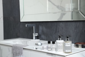 A bathroom with a sink, mirror and soap dispenser