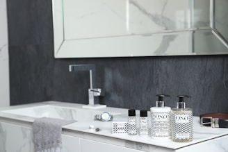 A bathroom with a sink, mirror and soap dispenser