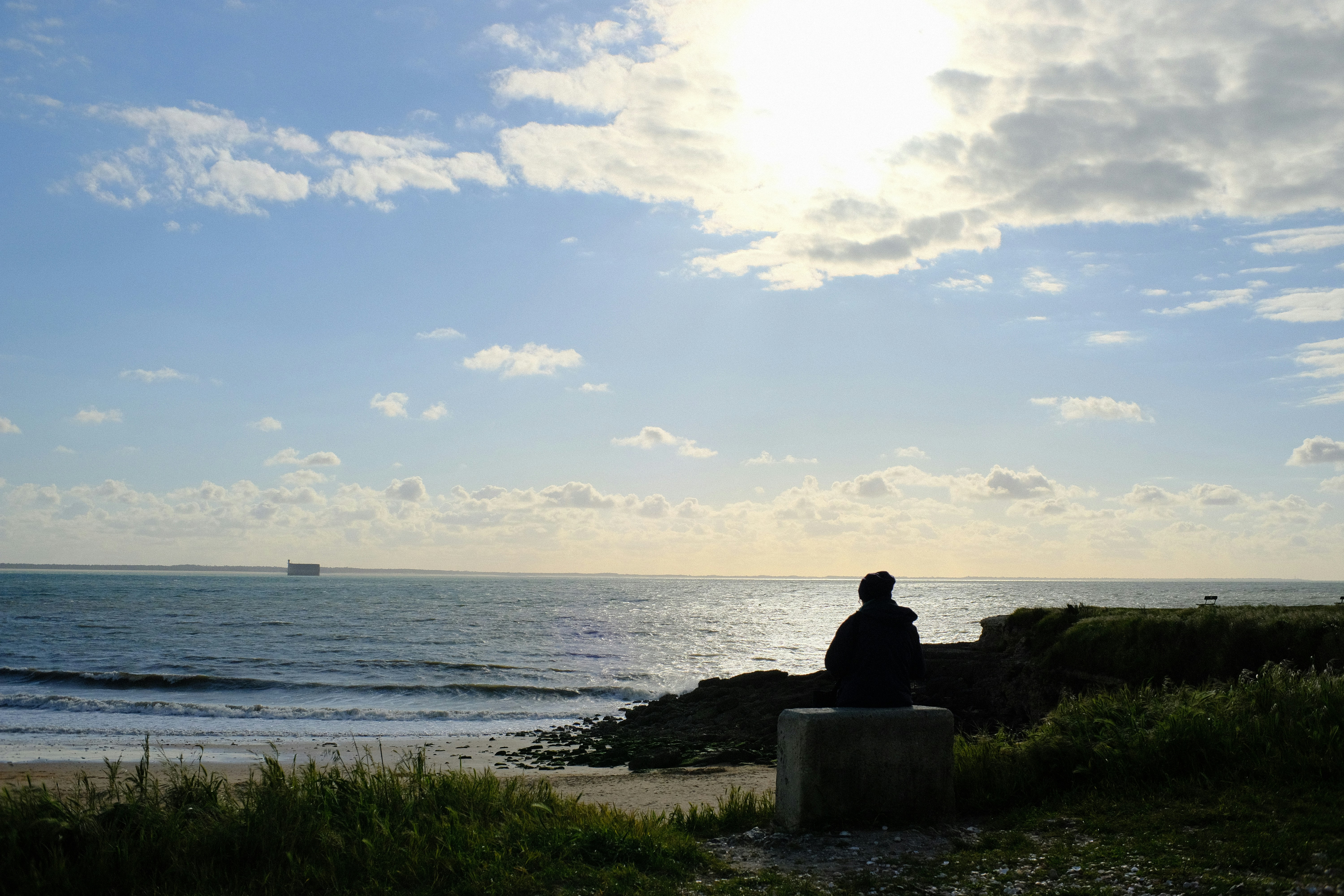 A person sitting on a bench looking out at the ocean photo – Free Île-d ...