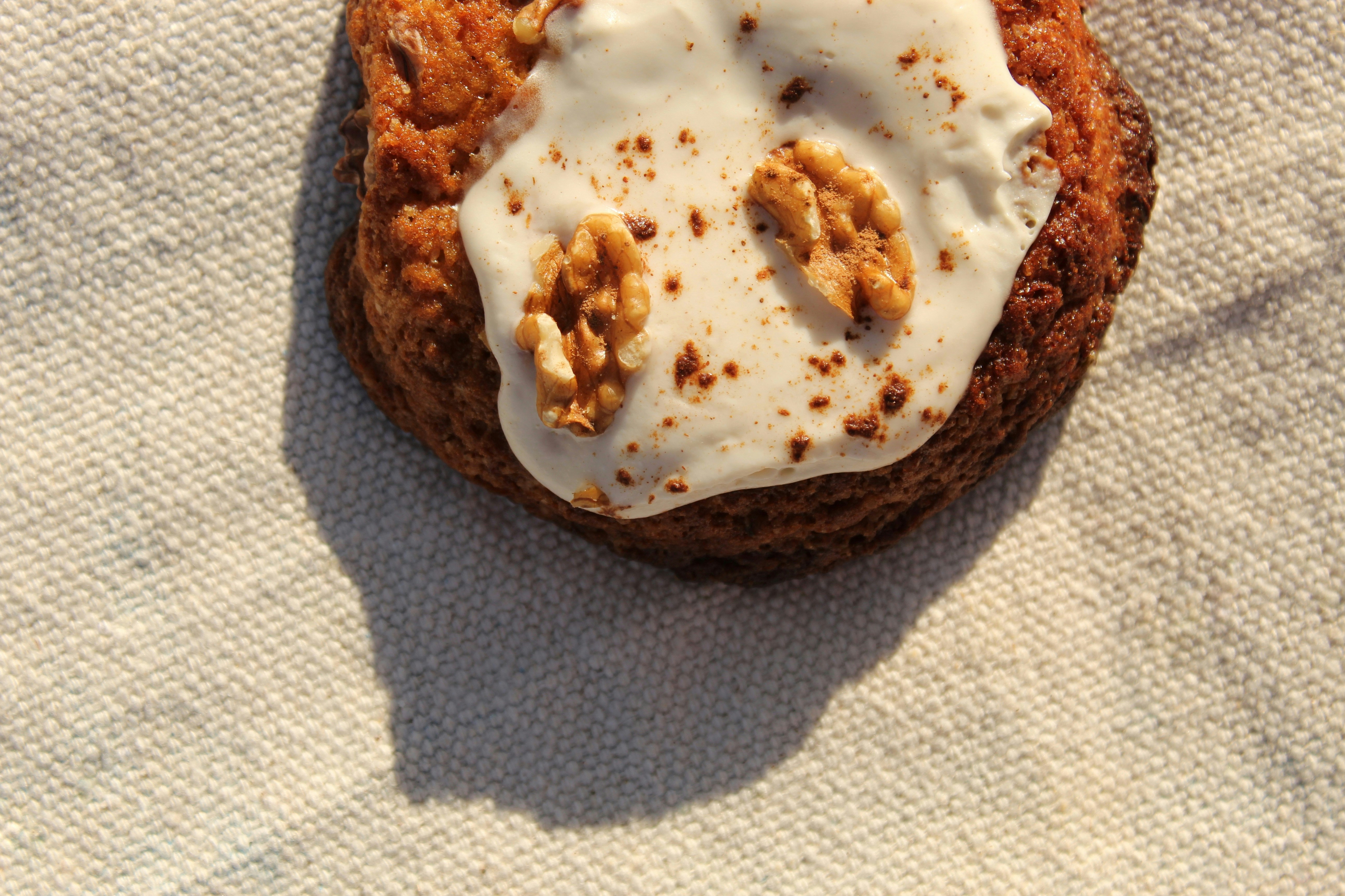 A cookie with white frosting and walnuts on top