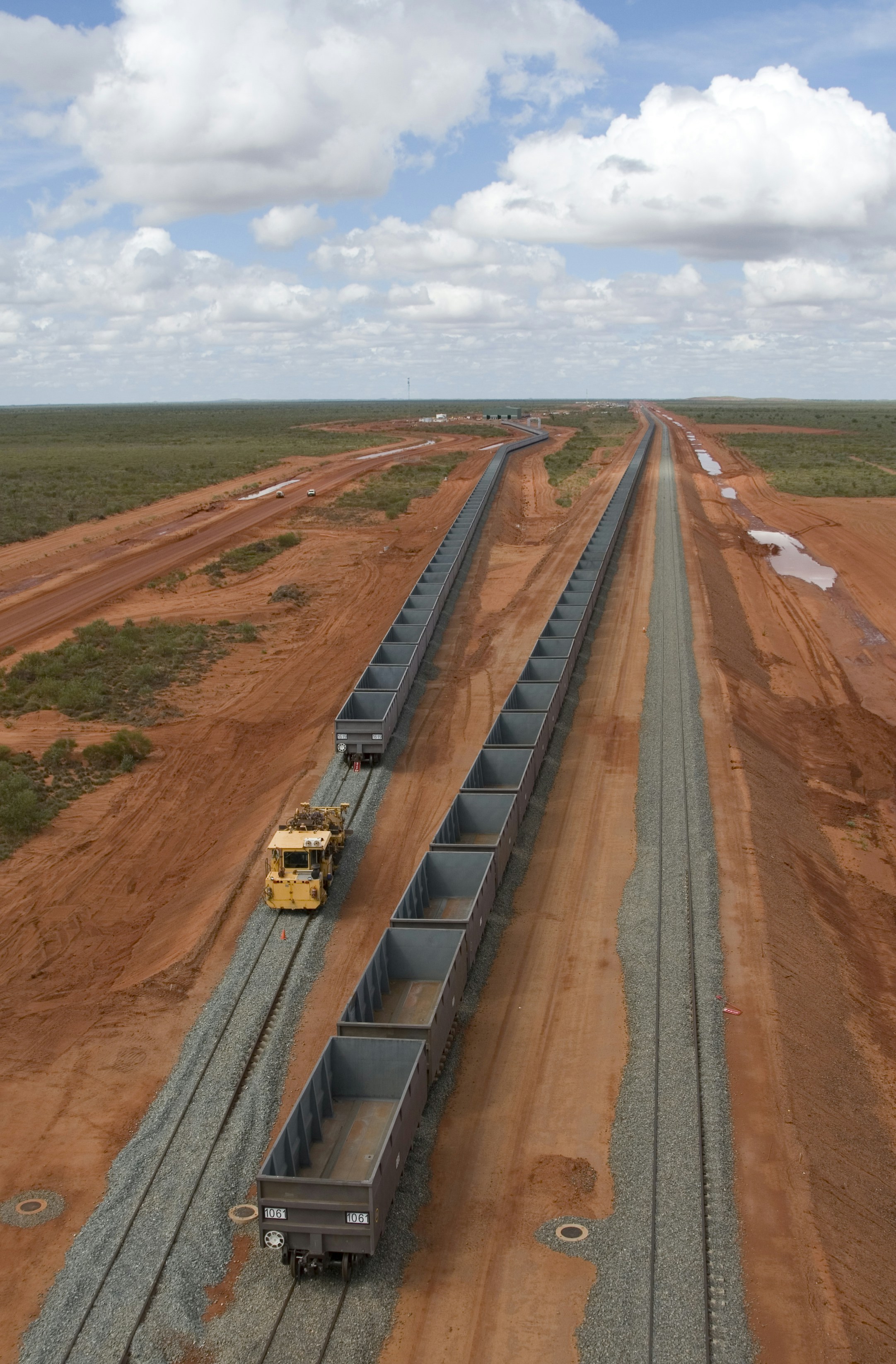 A train traveling down tracks next to a dirt field