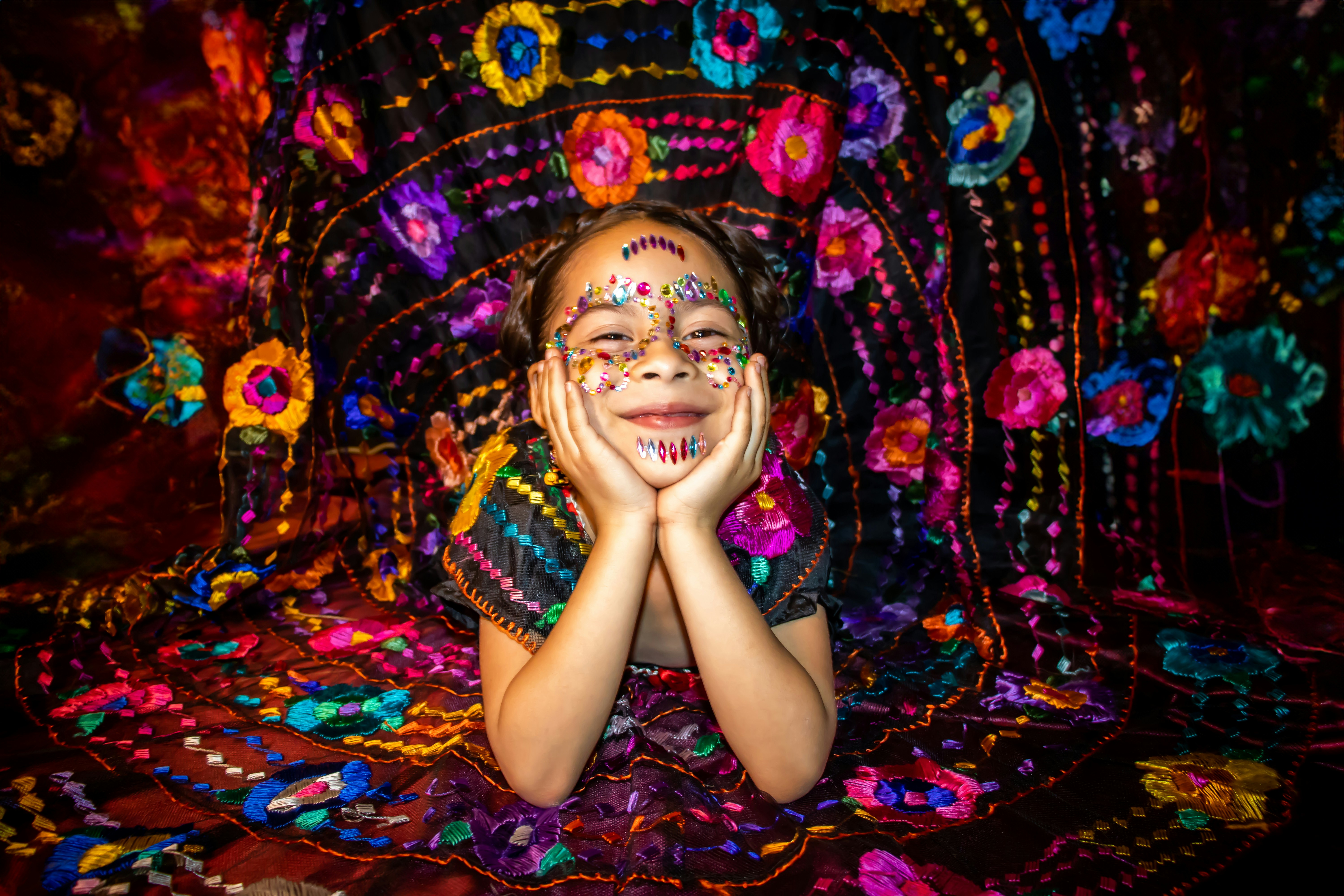A woman with painted face sitting on a colorful blanket