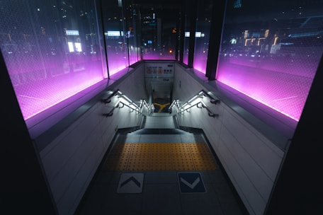A train station with purple lights on the walls