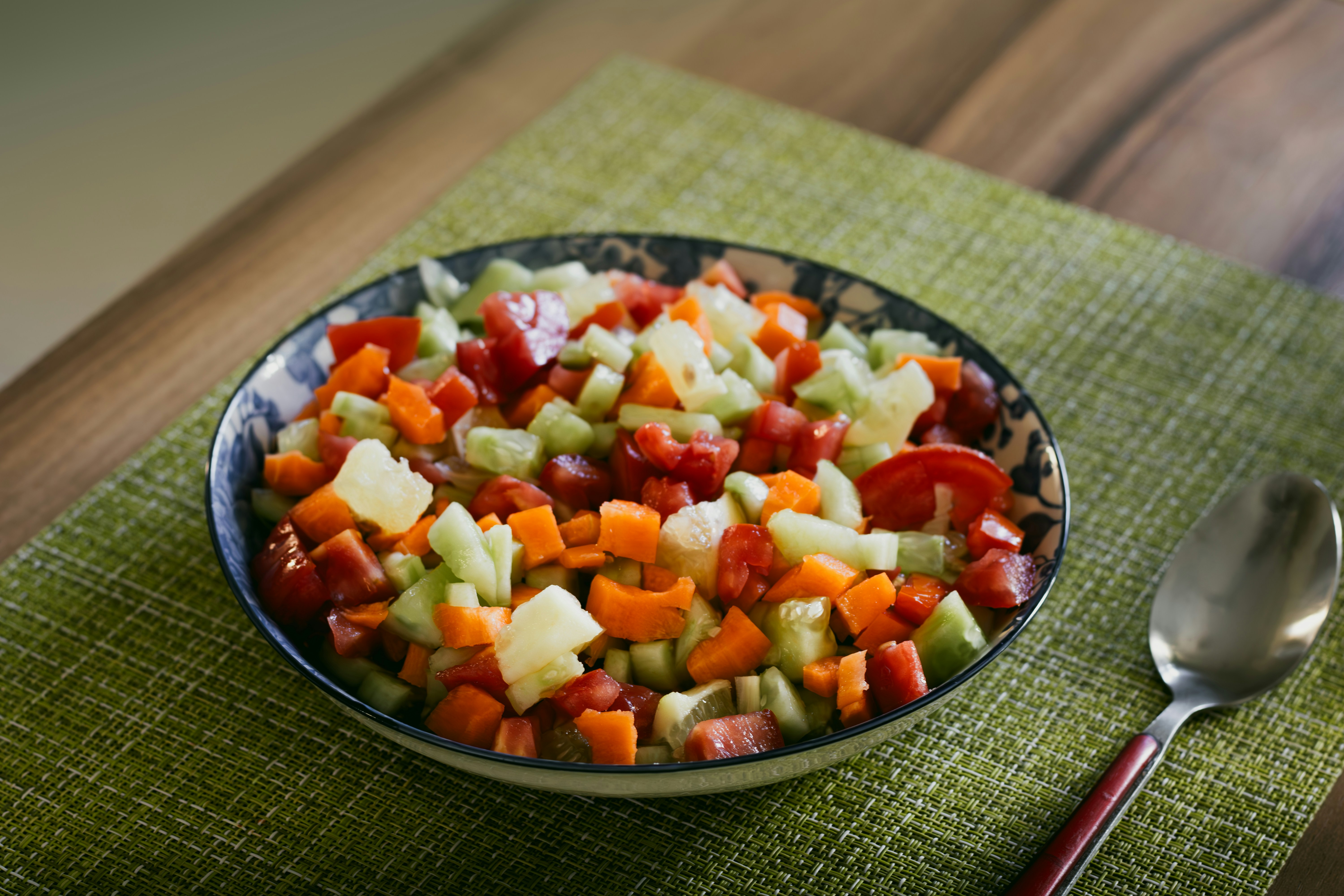 A bowl of chopped vegetables with a spoon