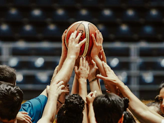 A group of people reaching for a basketball