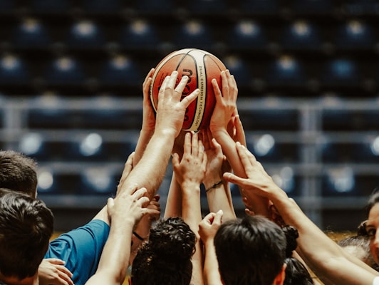A group of people reaching for a basketball