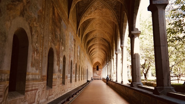 A long hallway with arches and a clock on the wall