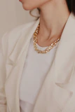 A woman wearing a white jacket and a gold necklace