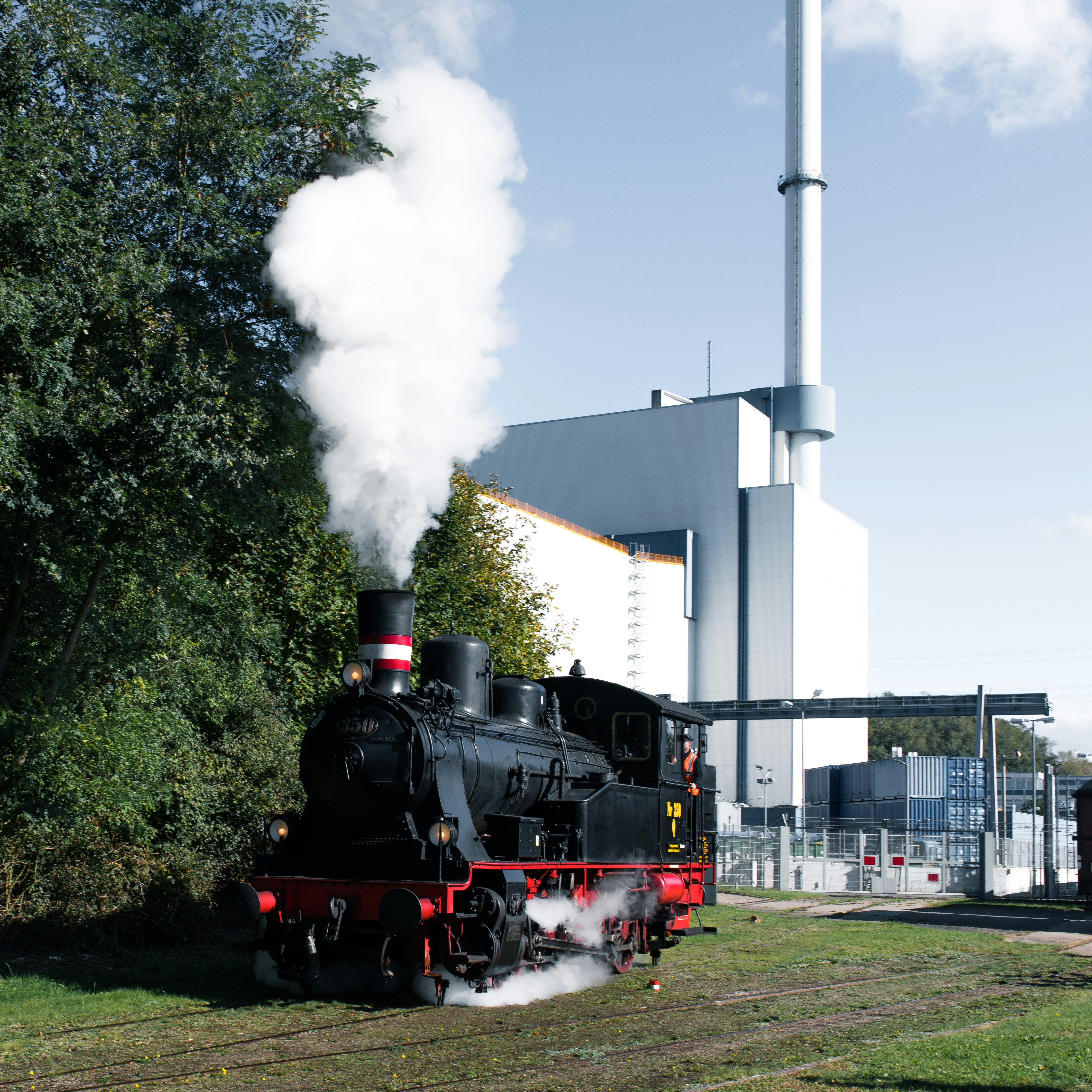A black and red train traveling past a tall building