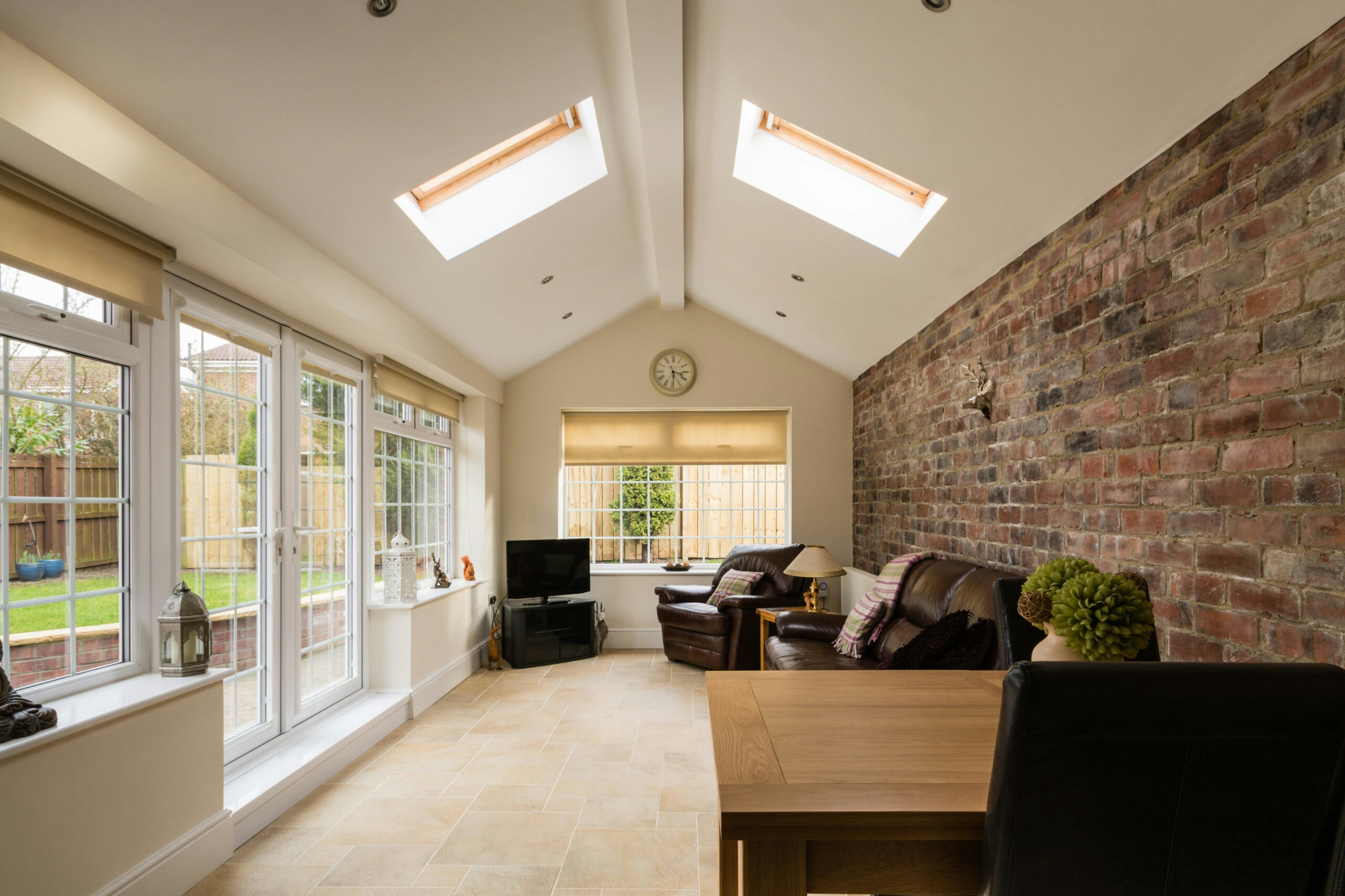 Panoramic sunroom with full-length windows overlooking a garden, bright interior with comfortable seating