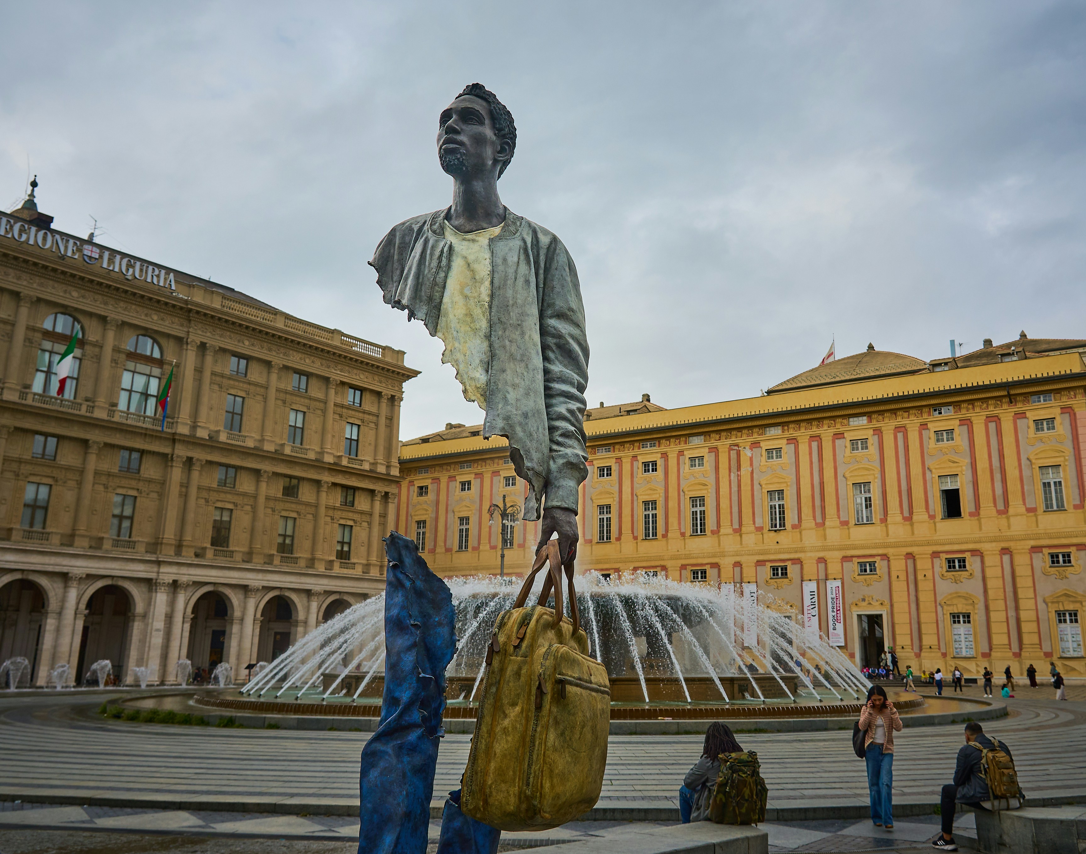 A statue of a man holding a bag in front of a fountain