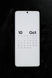 A person holding a white tablet with a calendar on it