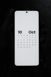 A person holding a white tablet with a calendar on it