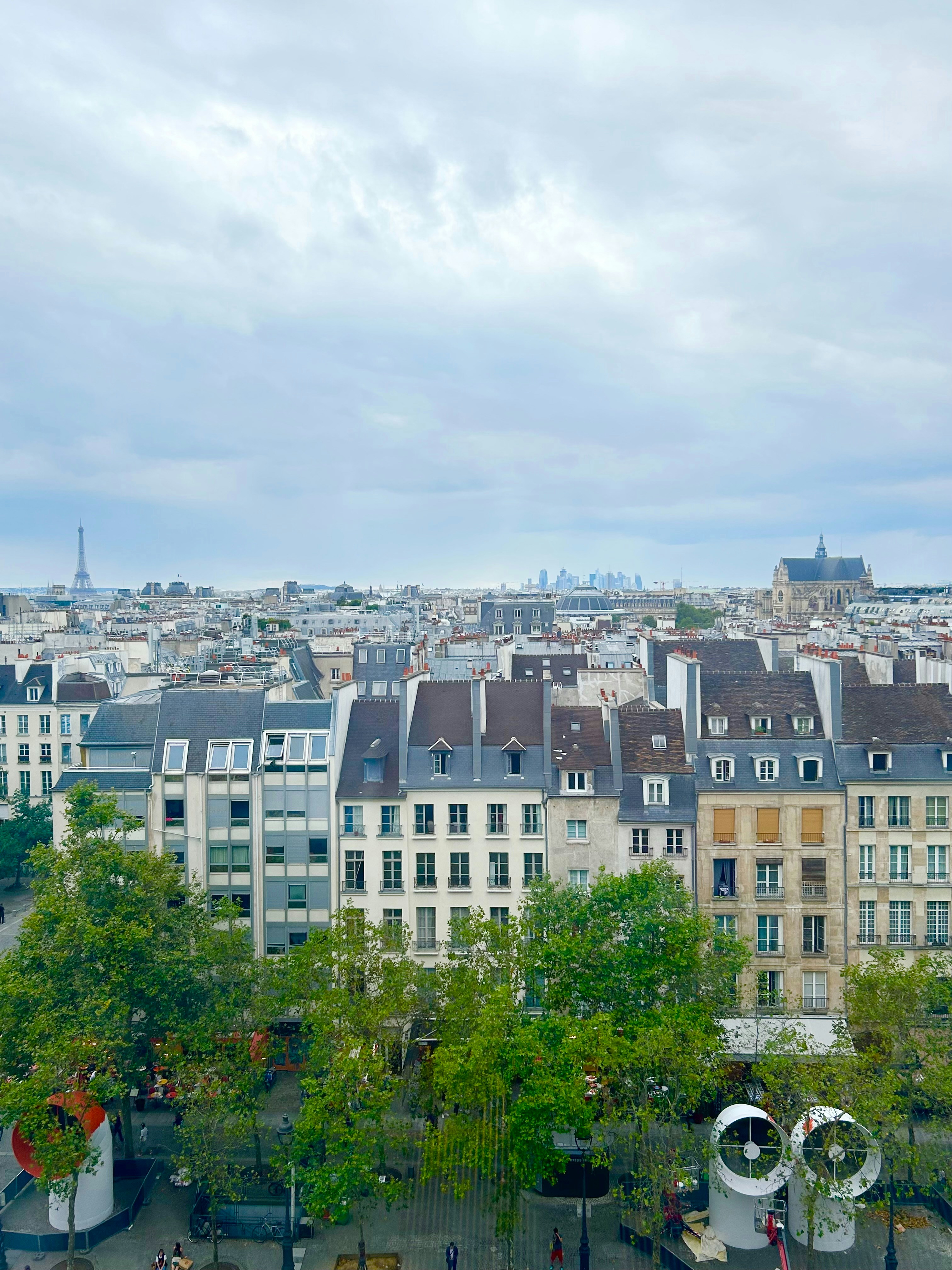 Fashion editorial shot, elegant structured black dress on model, Parisian rooftop, moody overcast sky