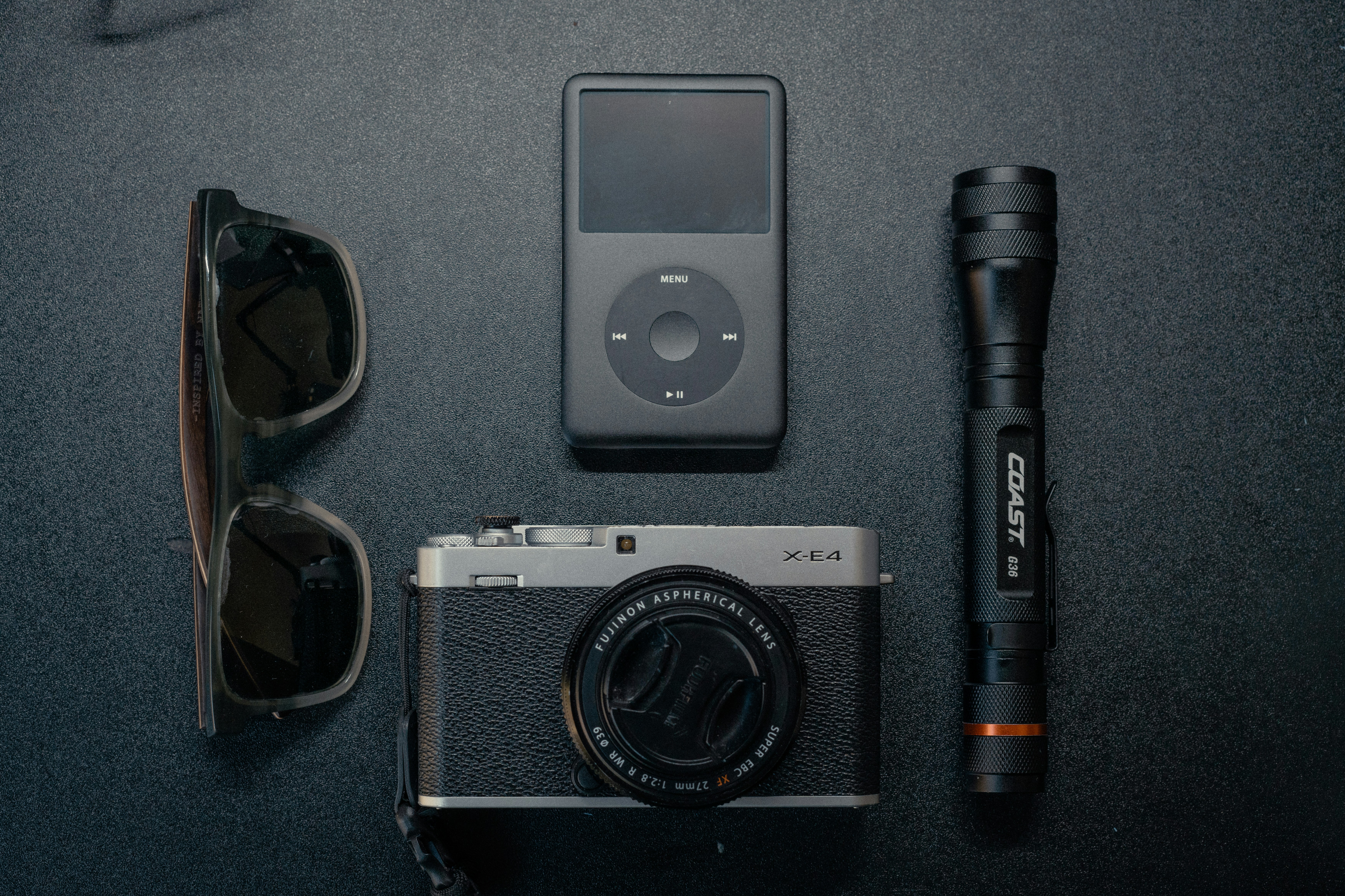 A camera, sunglasses, umbrella, and other items laid out on a table