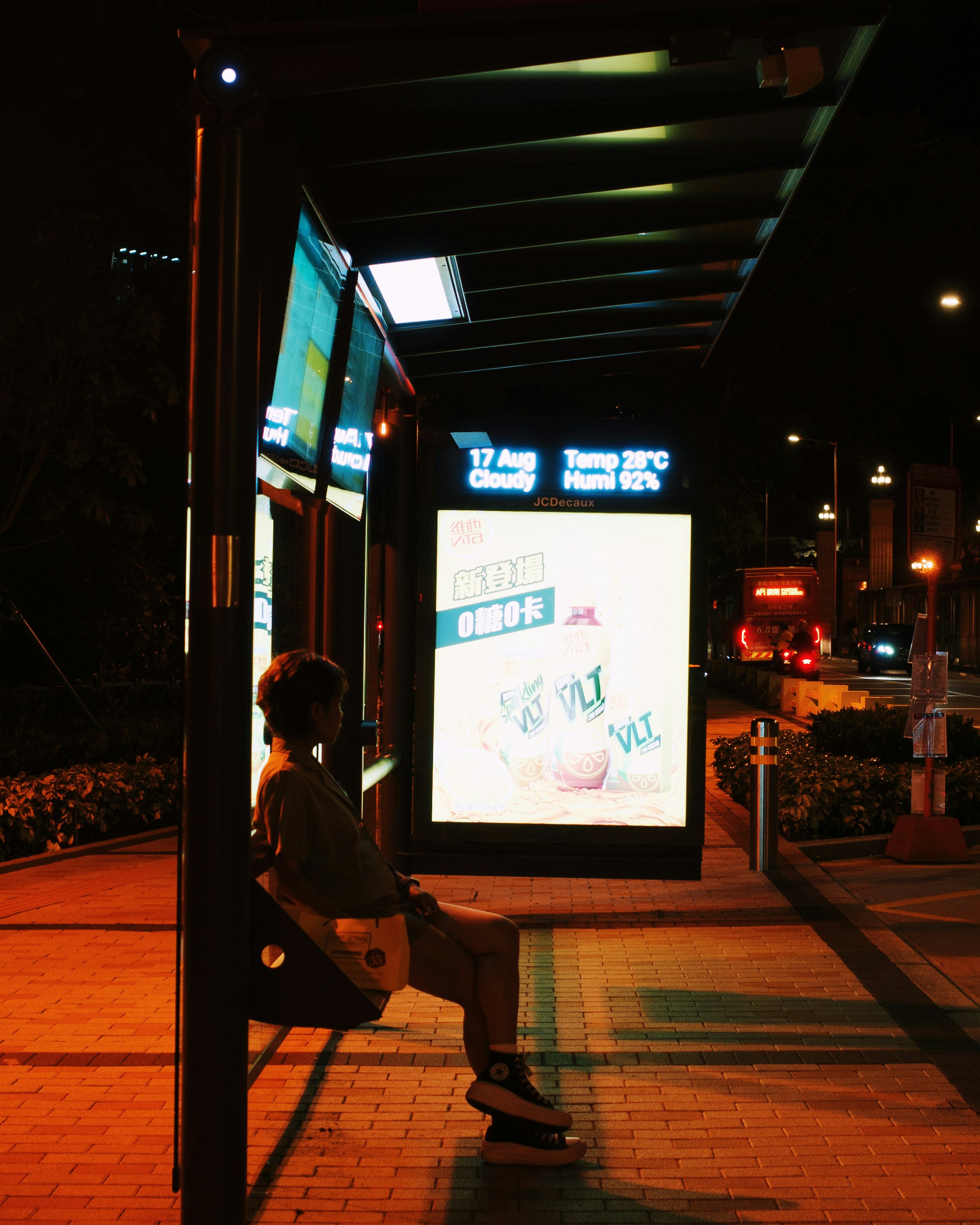 A person sitting on a bench in front of a bus stop