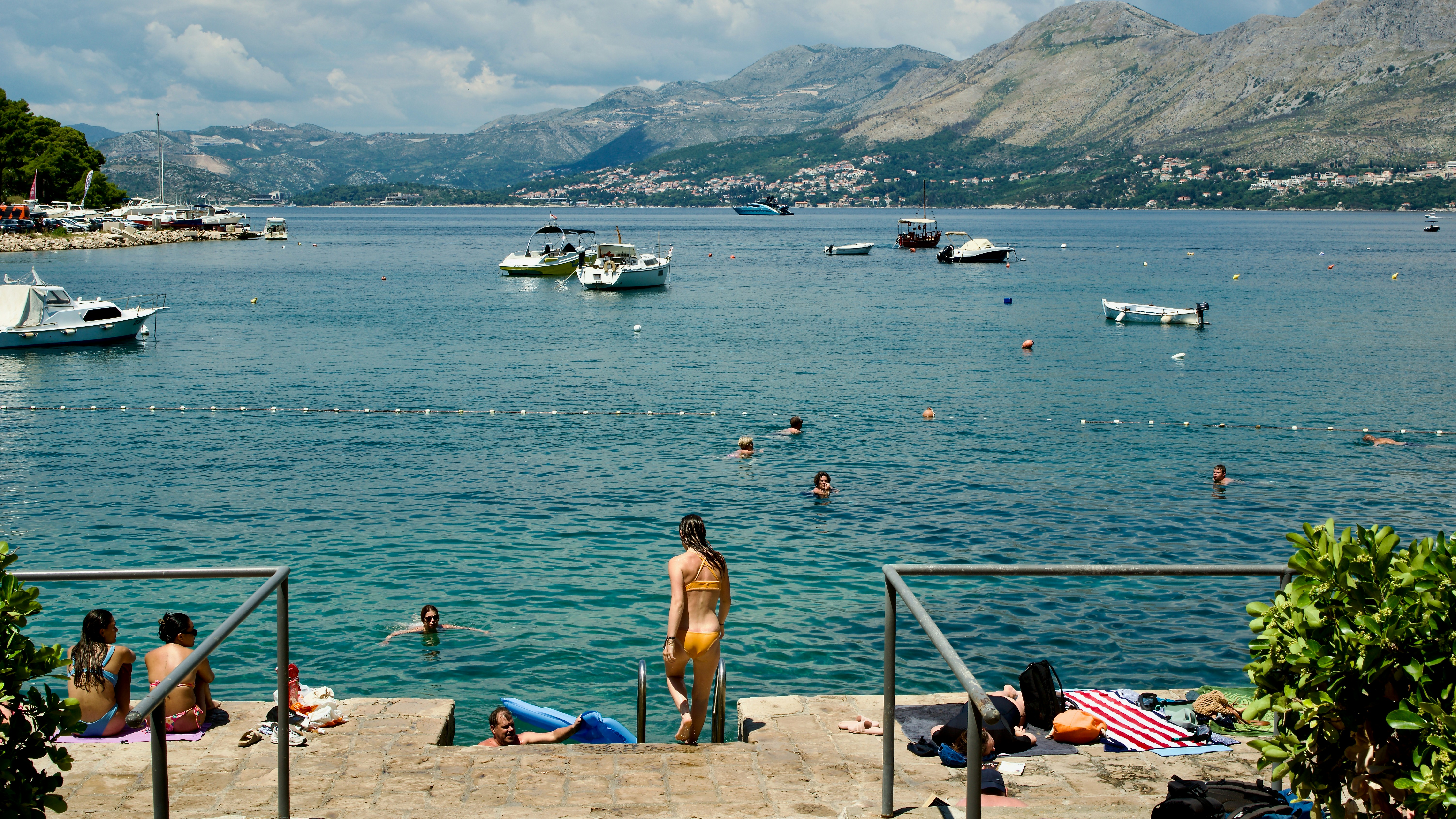 A group of people sitting on top of a beach next to a body of water