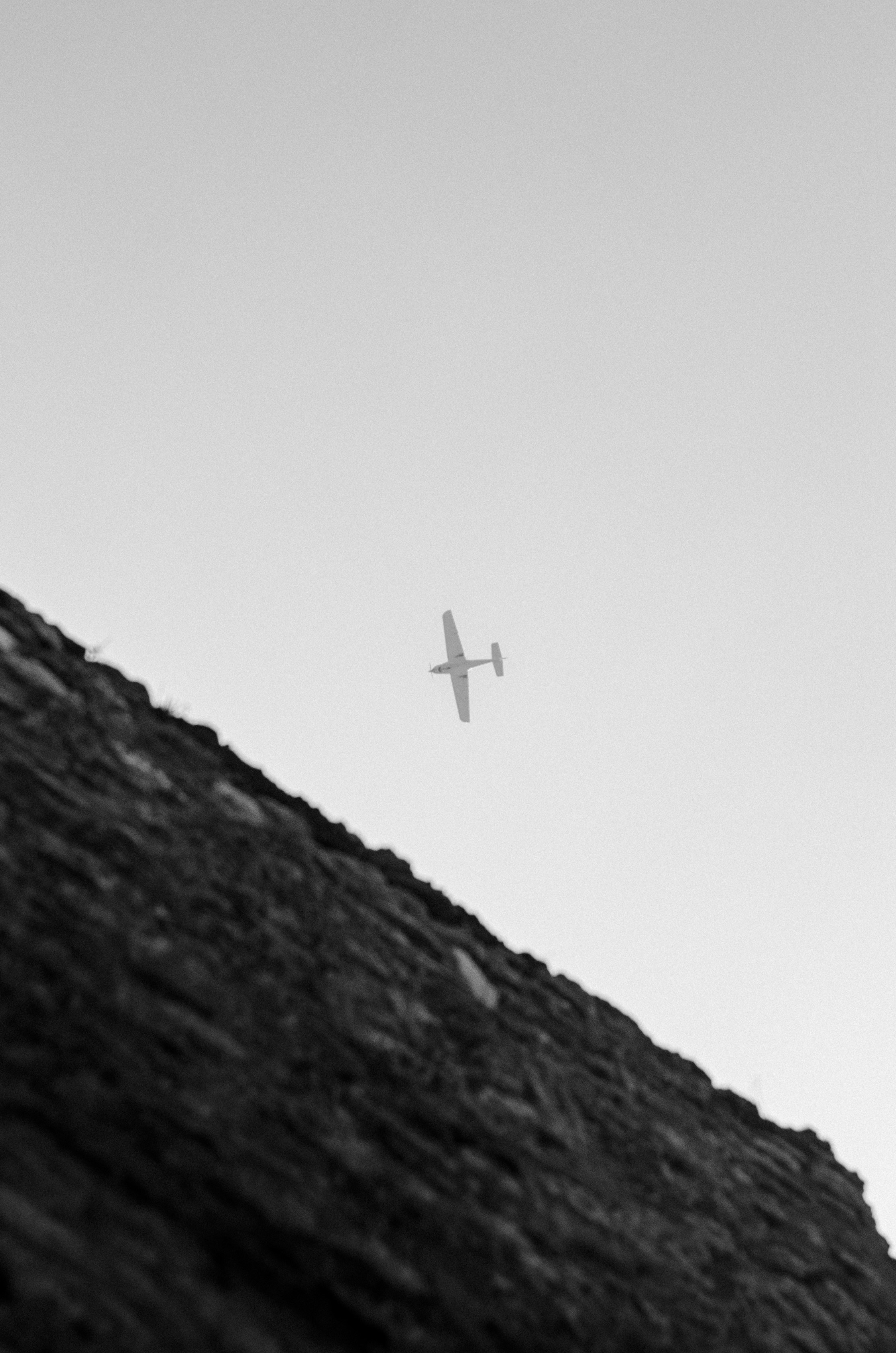 A small plane flying over a rocky mountain