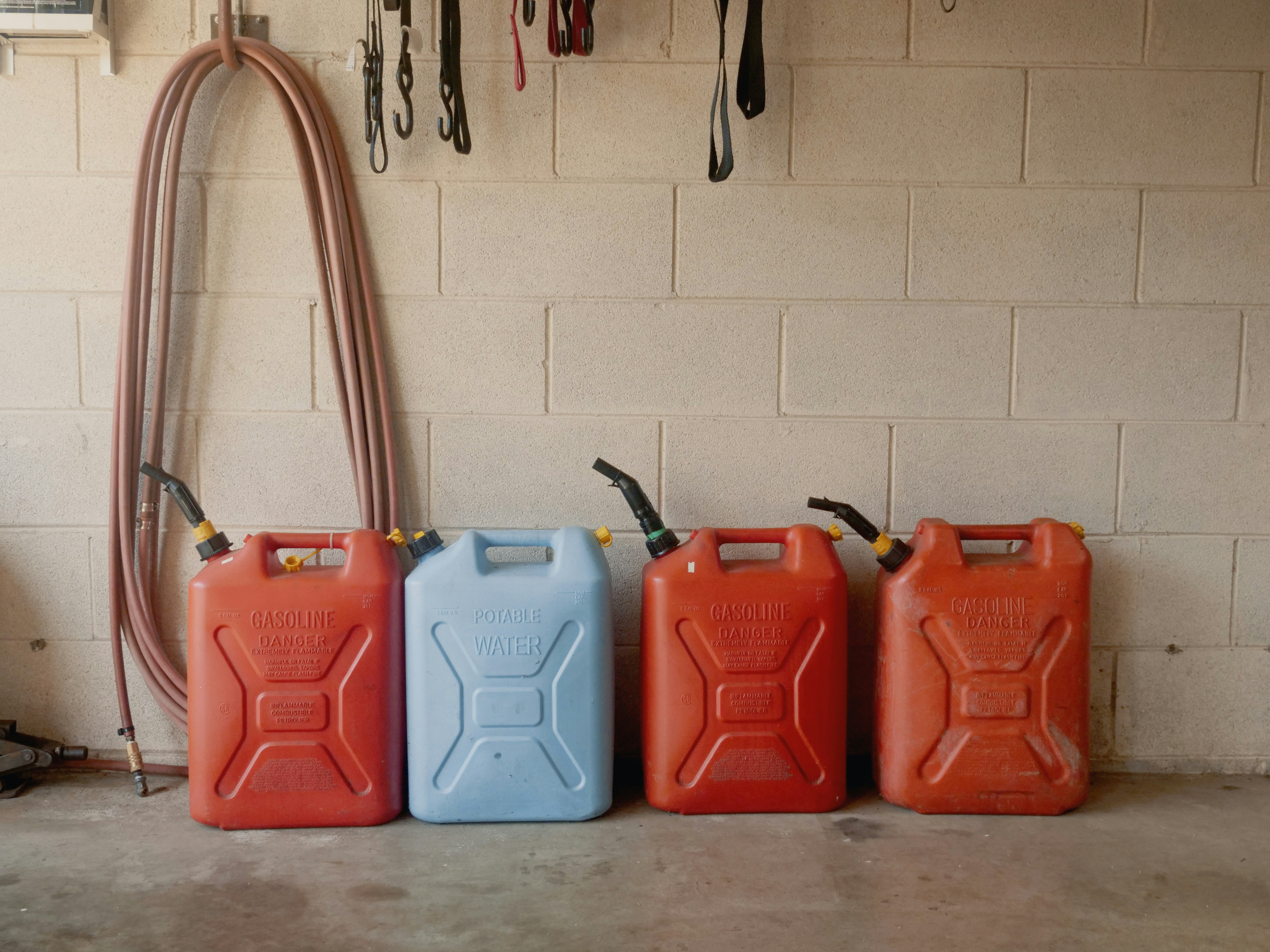 A row of gas cans sitting in front of a wall