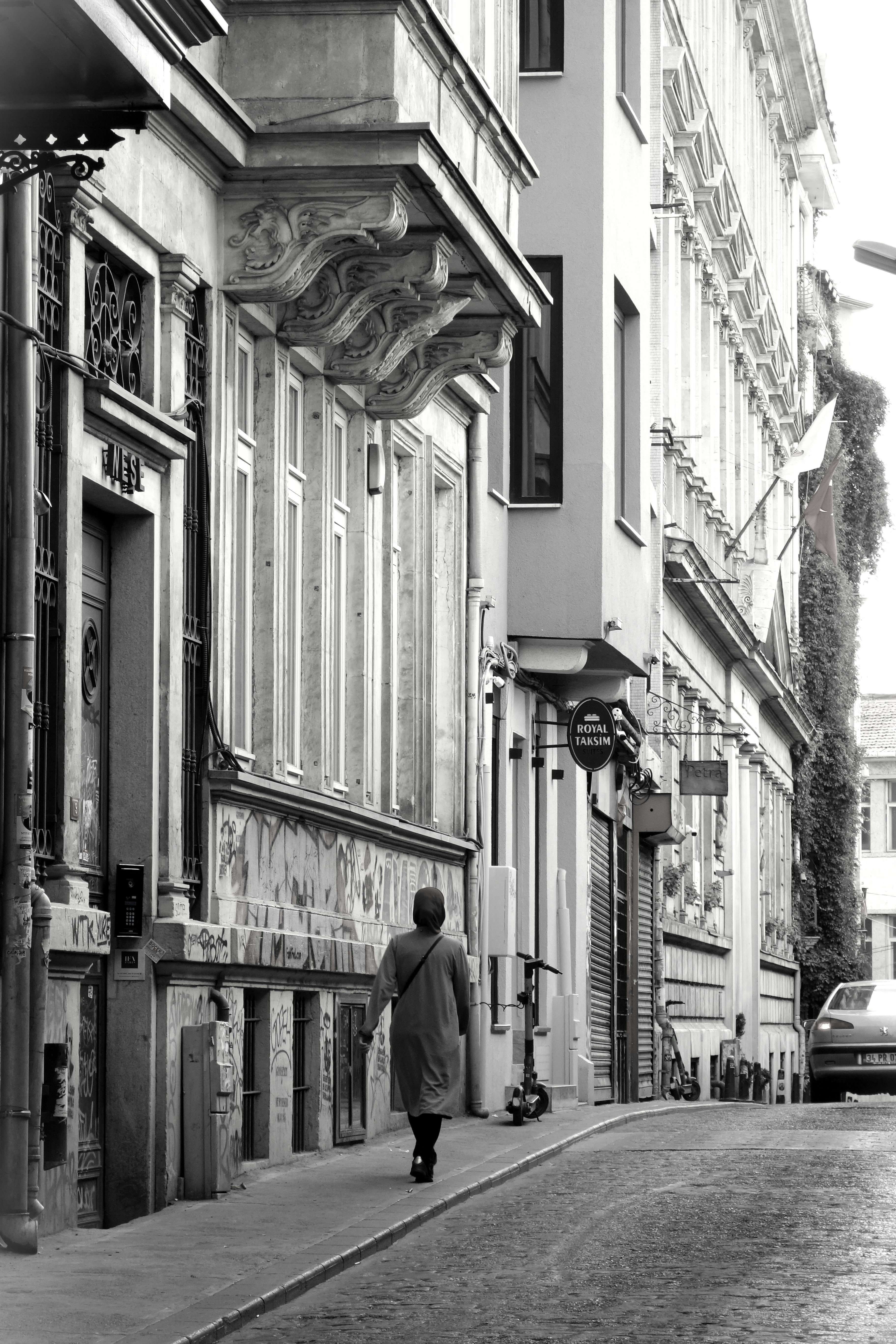 A man walking down a street next to tall buildings