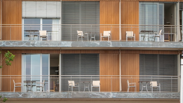 A tall building with balconies and chairs on the balconies