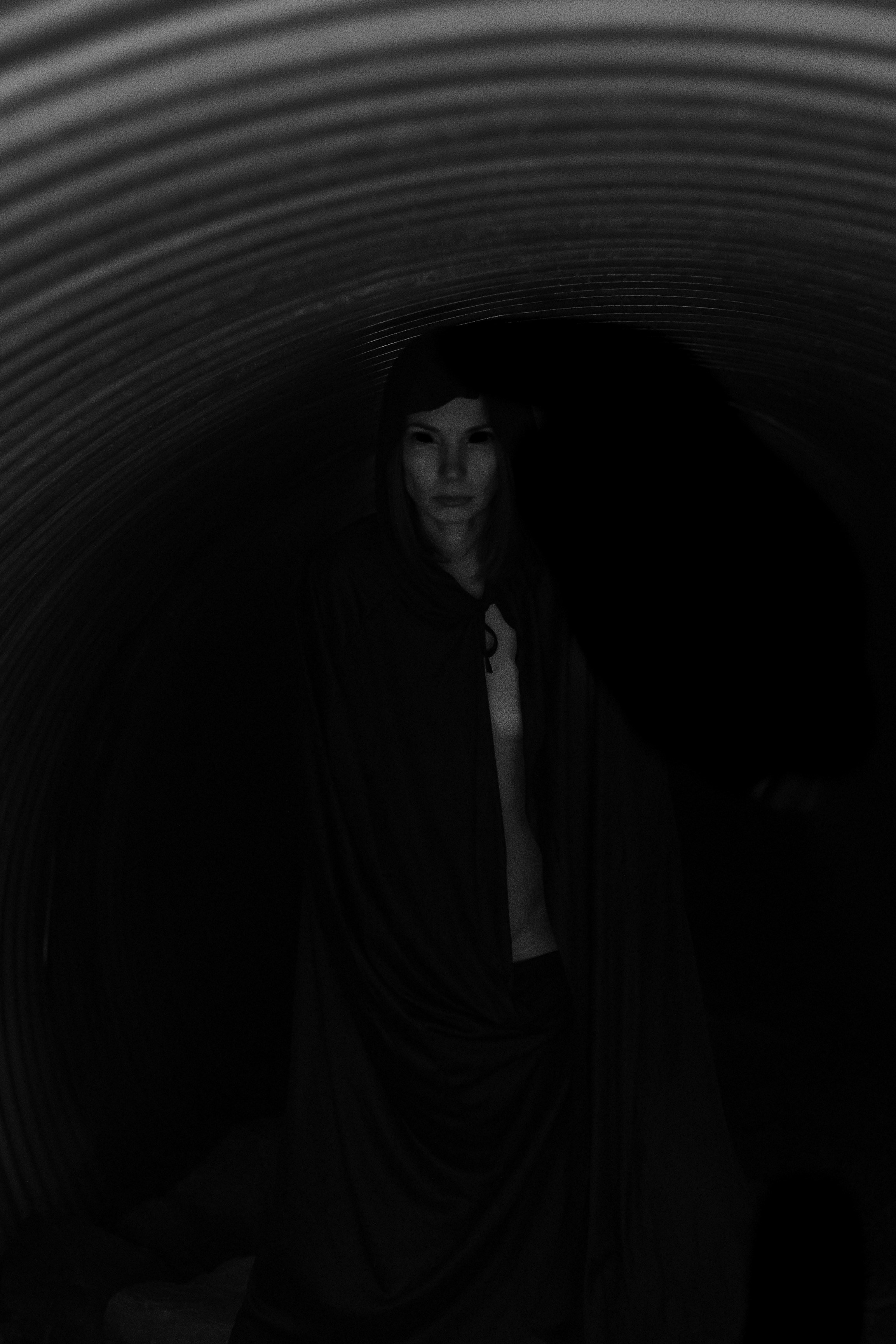 A woman standing in a dark tunnel with a scarf around her neck