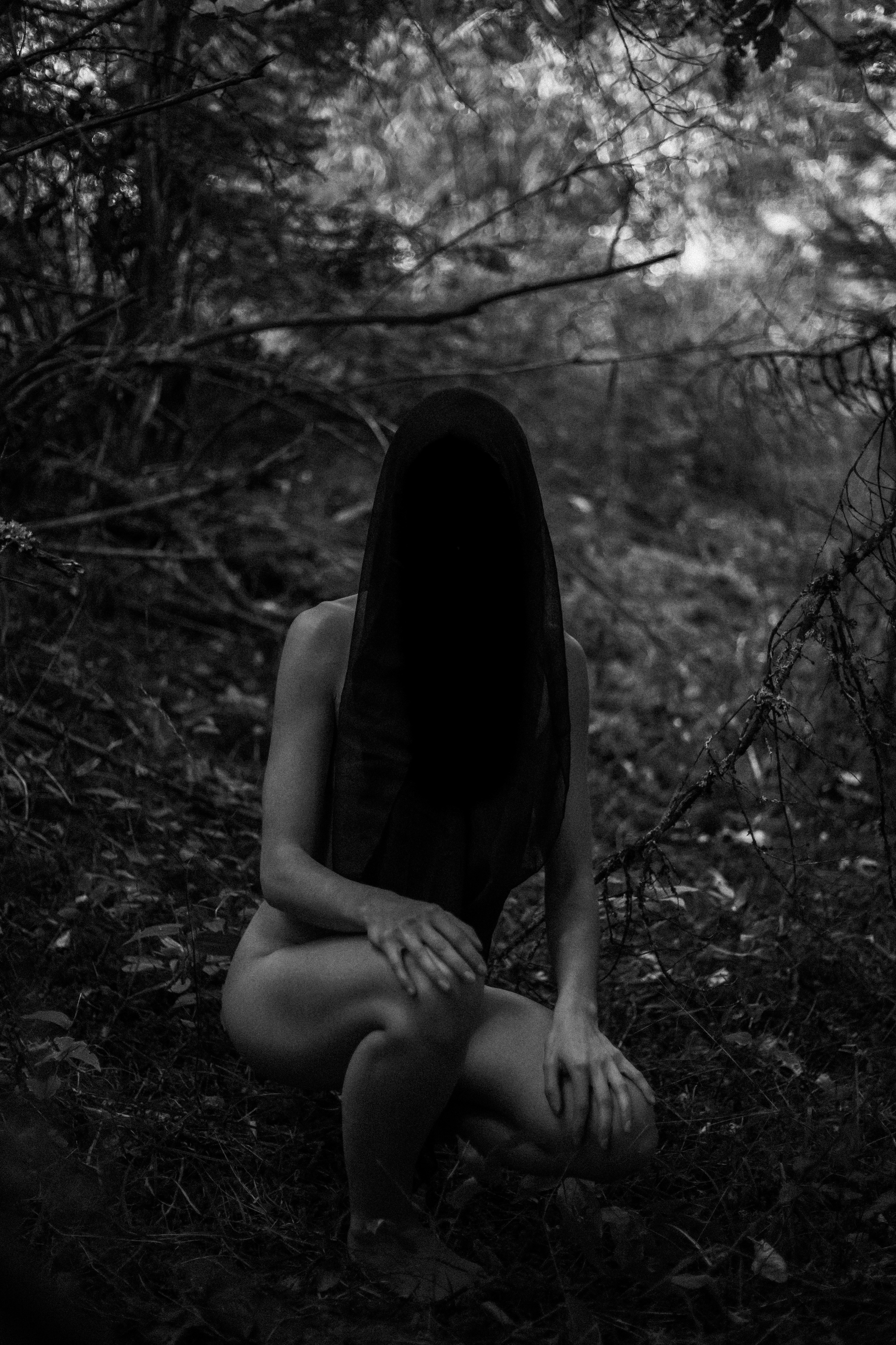 A woman is sitting in the woods alone