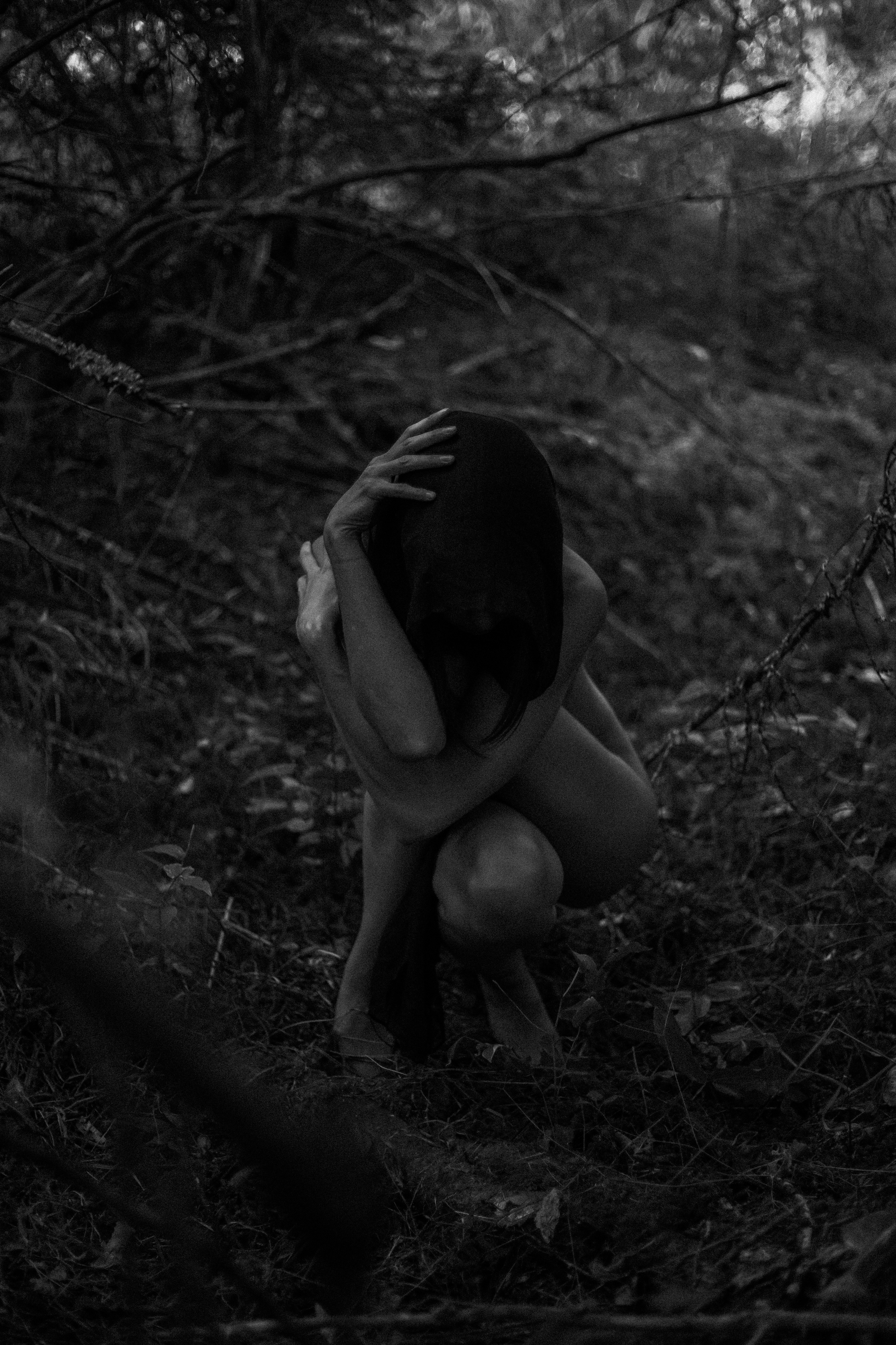 A woman sitting in the woods with her head in her hands