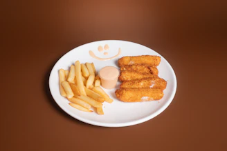 A white plate topped with fried food next to a pile of fries