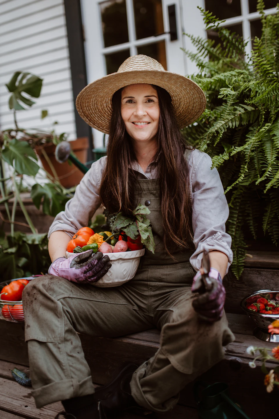 A woman sitting on a bench with a bowl of fresh vegetables