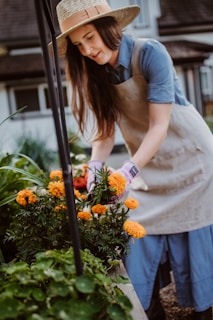 A woman in an apron and hat tending to flowers