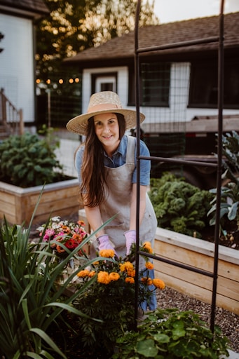 A woman wearing a hat and gardening gloves