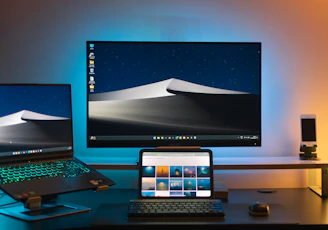 A desk with two monitors and a laptop