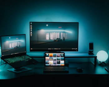 A desk with two monitors and a laptop