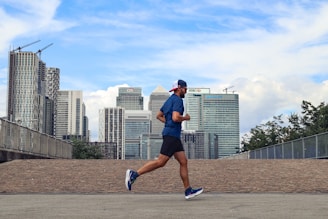 A man running in a city with tall buildings in the background