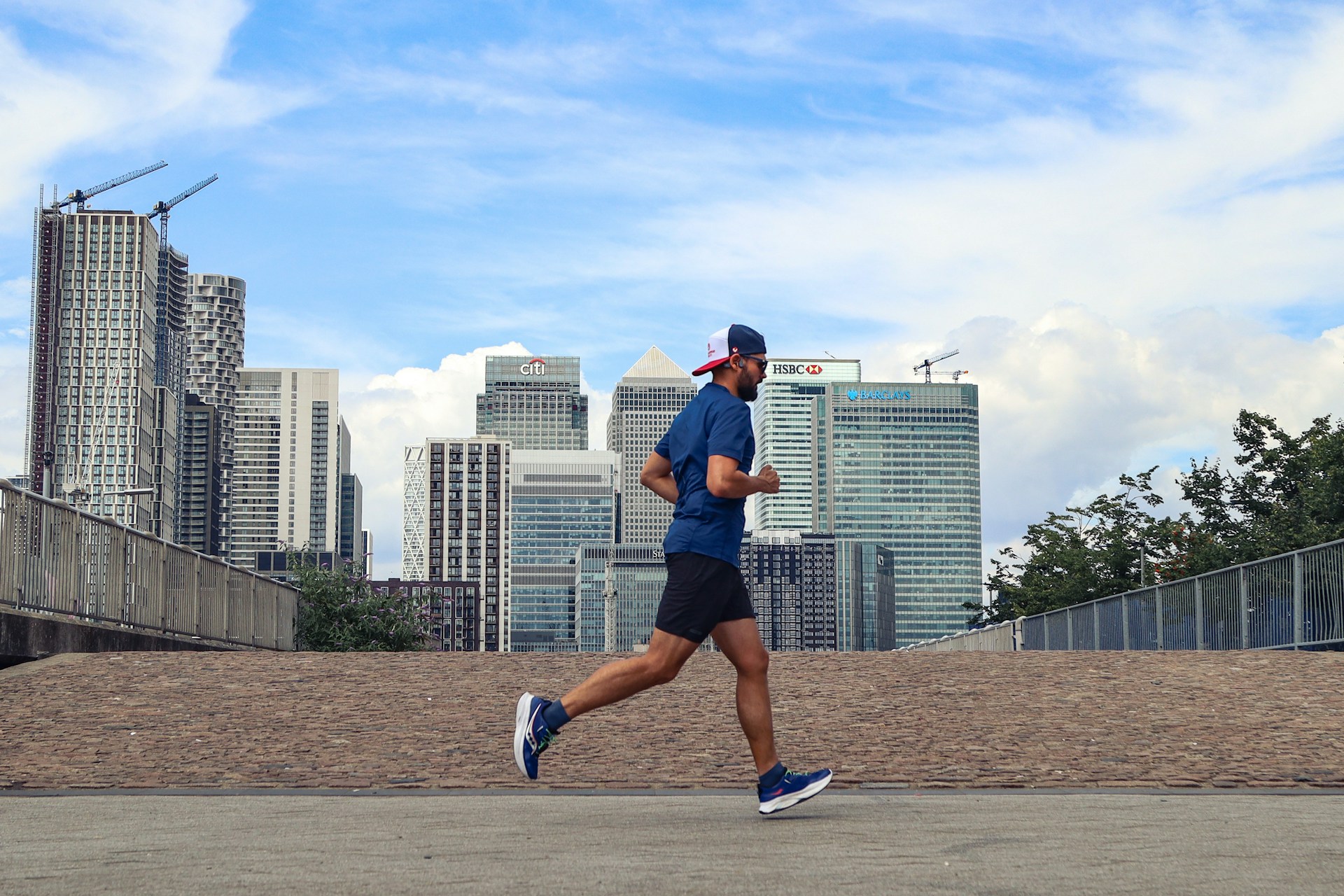 A man running in a city with tall buildings in the background