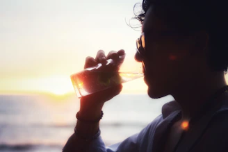 A man drinking from a wine glass in front of the ocean